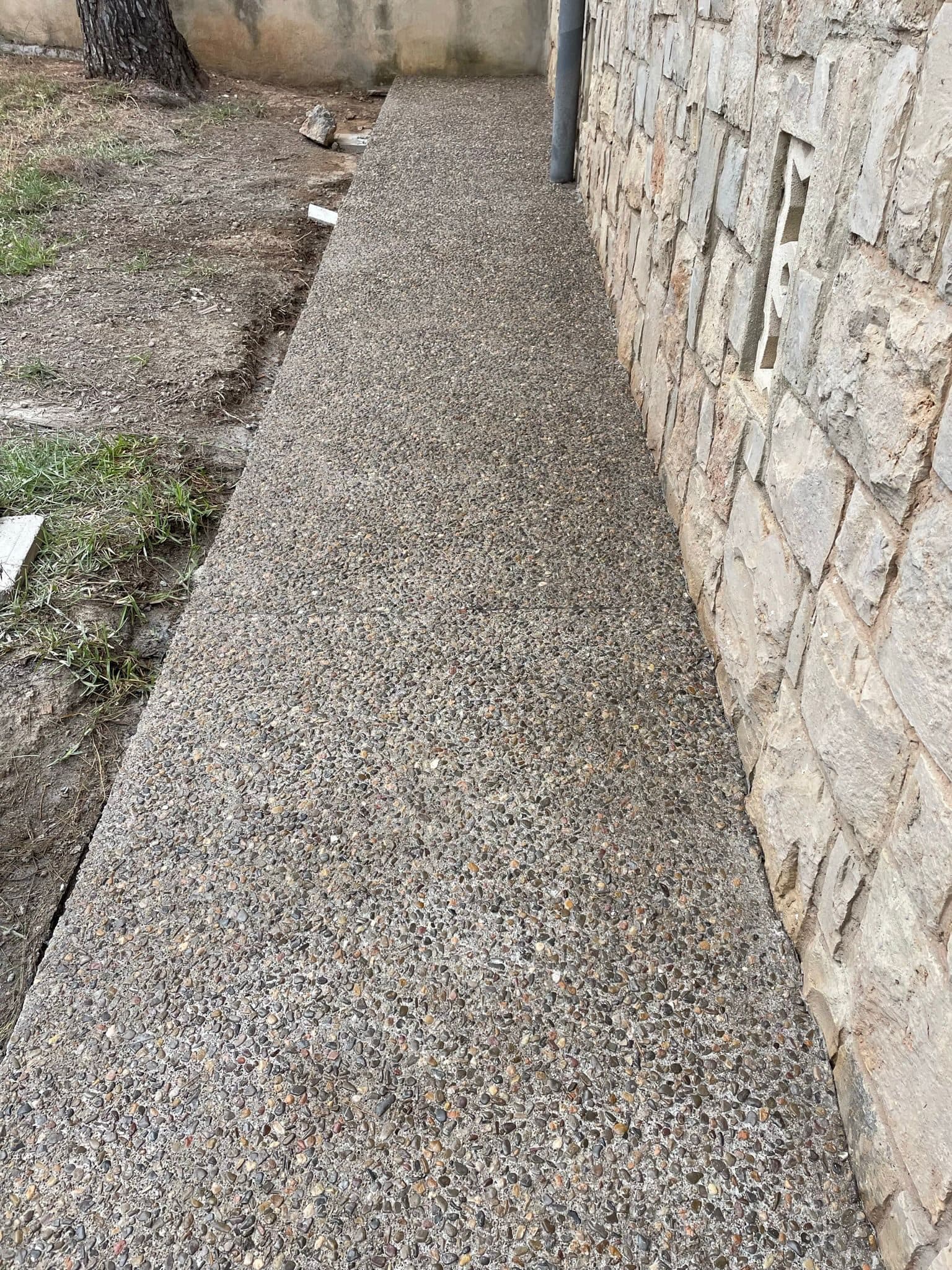 Paso lateral del jardín ejecutado en hormigón lavado con árido visto