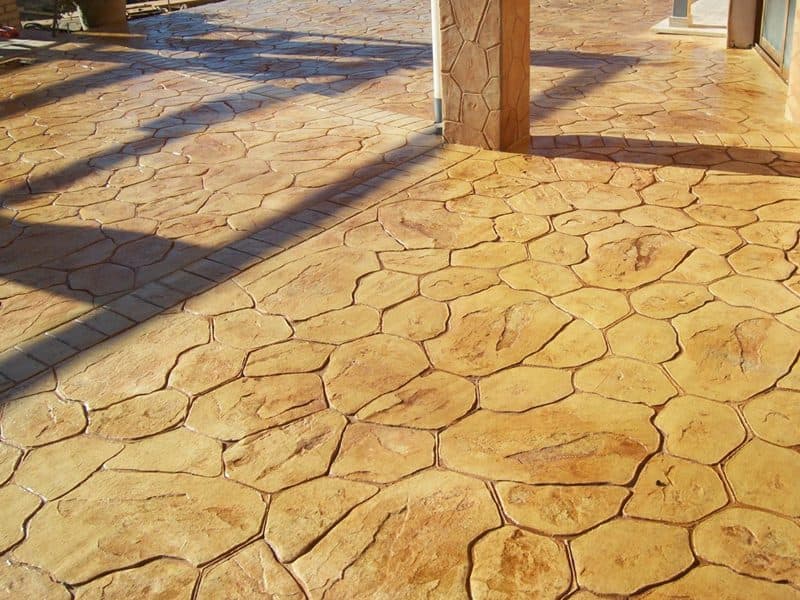 Zona pavimentada con piedra inglesa en tono crema bajo el porche