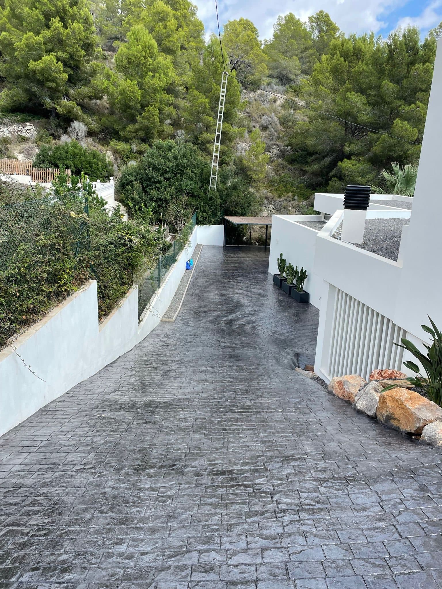 Rampa de acceso en hormigón impreso con molde de adoquín belga sobre terreno con desnivel