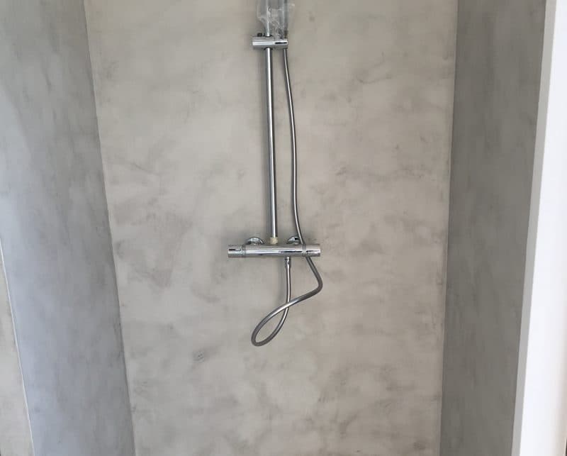 Ducha revestida en microcemento continuo tras la reforma completa del baño