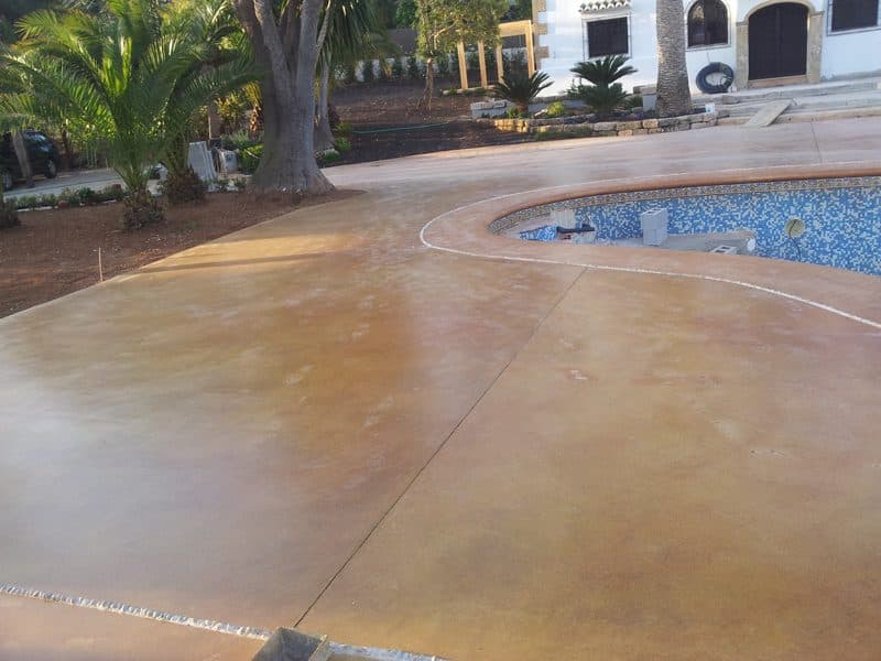 Hormigón pulido en tono crema alrededor de la piscina de una residencia con palmeras